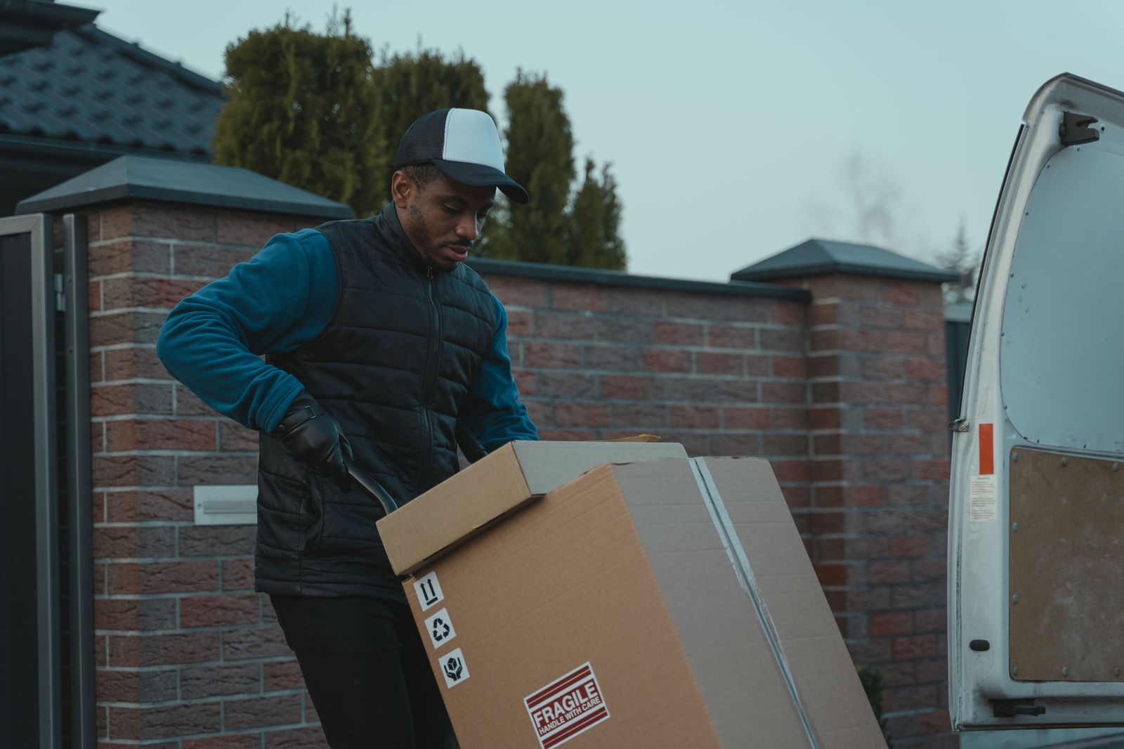 A chauffeur loads a suitcase into the trunk of a black sedan at the curb