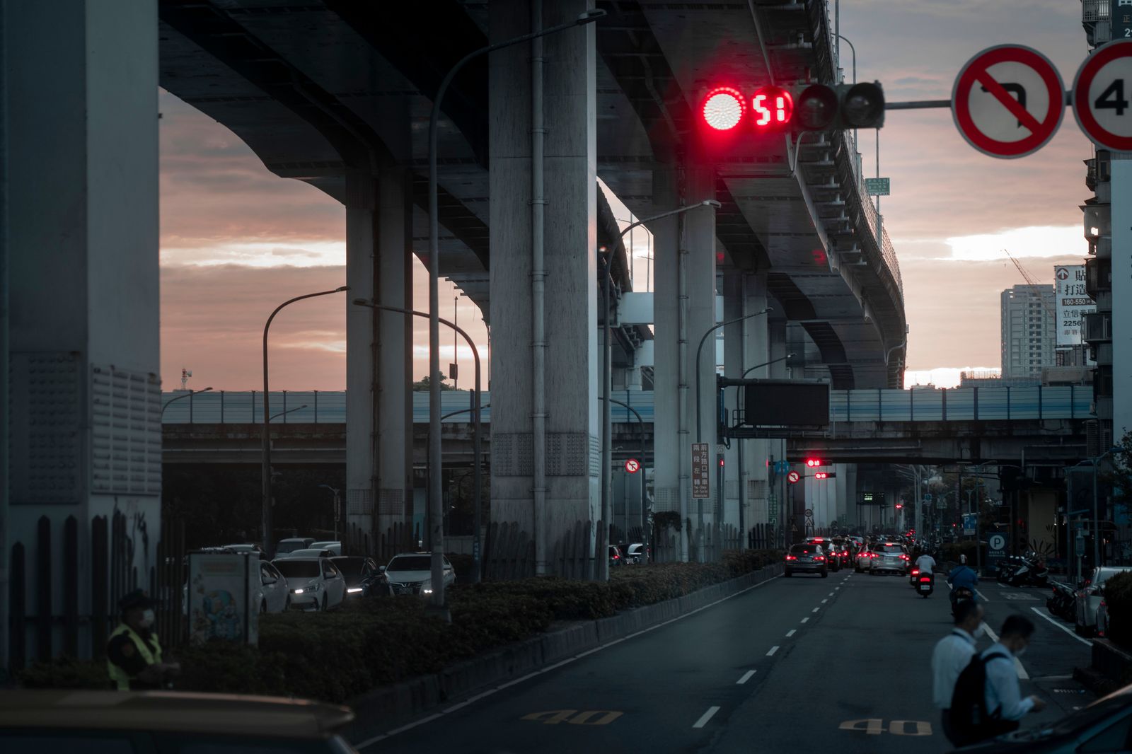 A black sedan on a highway overpass at dusk heading from Burlington towards the airport