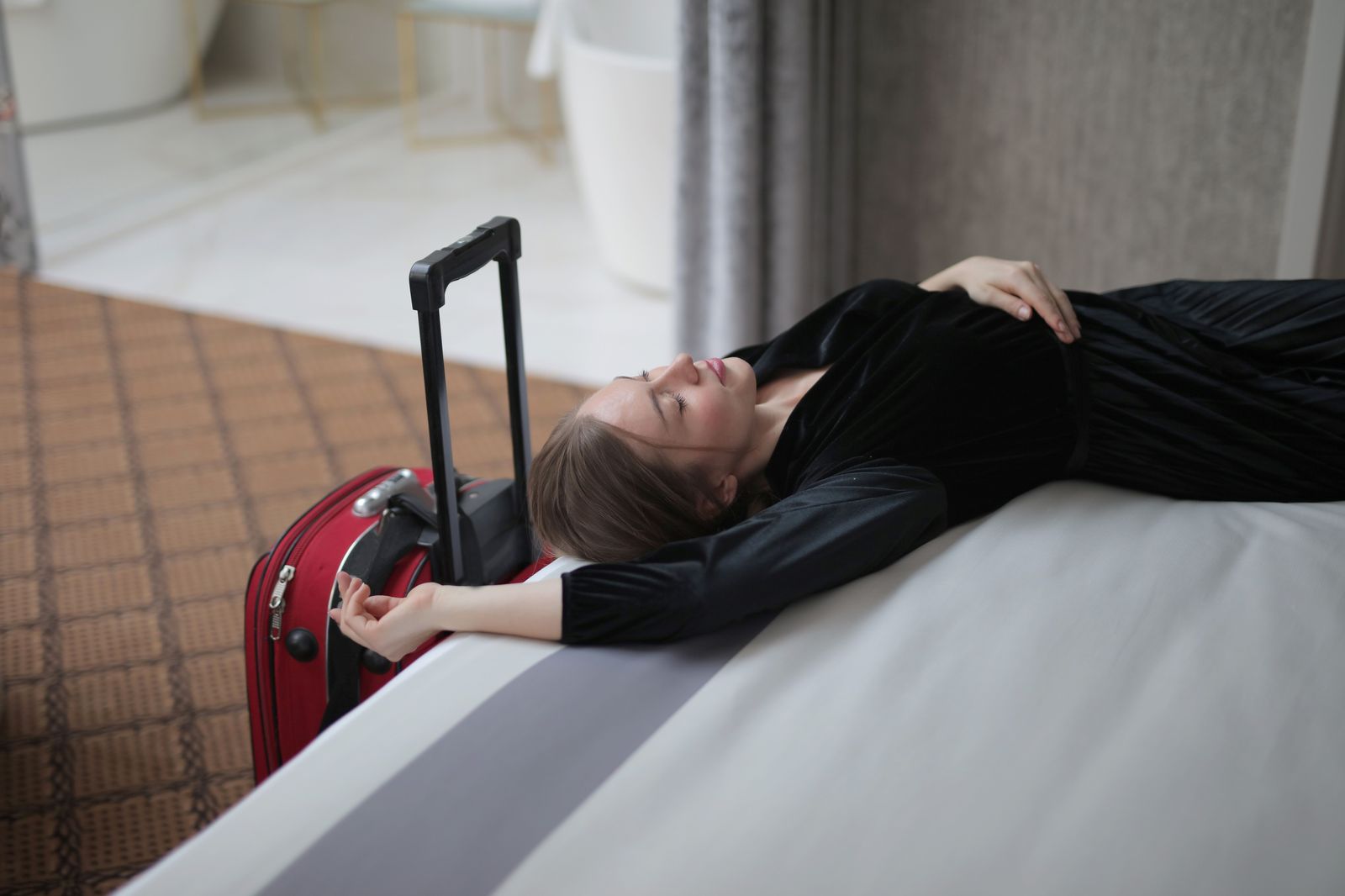 A traveller with a suitcase waiting at a hotel curb for a pre-booked car