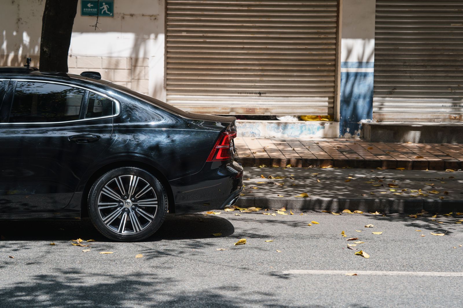 A chauffeur holding the rear door of a black sedan outside a restaurant