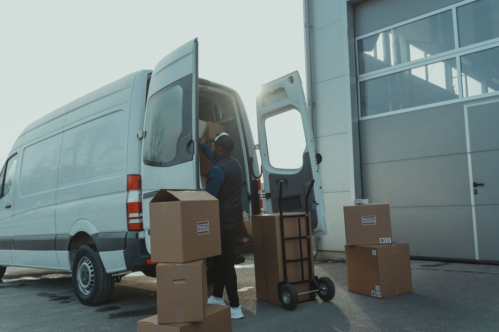 A chauffeur loading suitcases into the back of a van