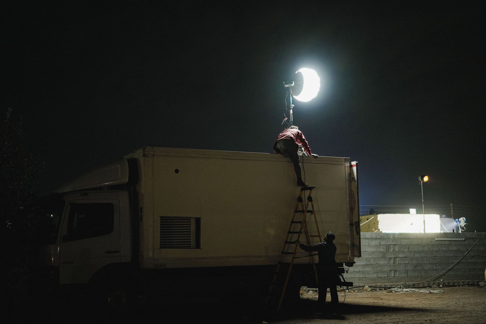 Film lights and production trucks at a night location