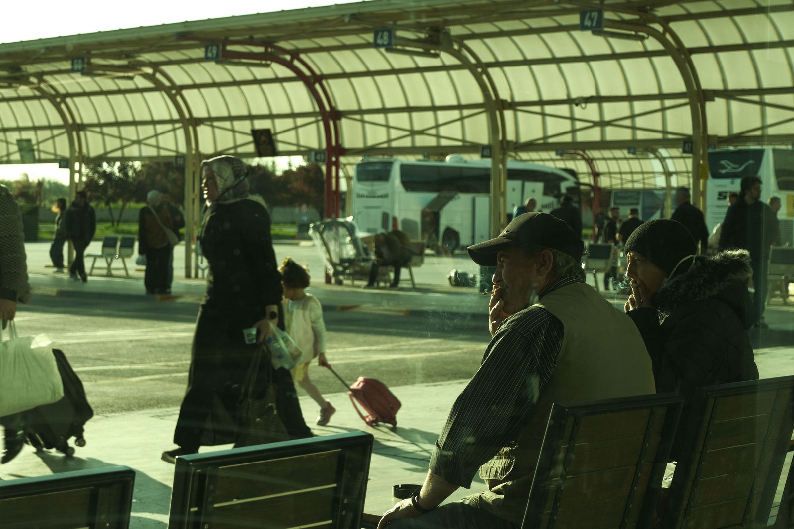 Commuter buses lined up at a bus terminal platform in the evening