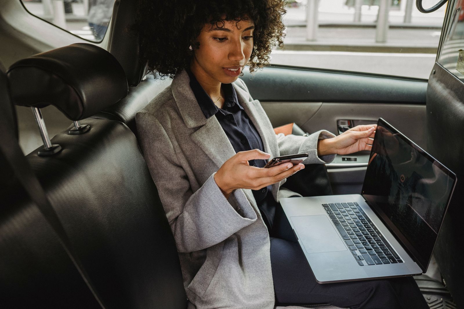 A passenger working on a laptop in the back seat during a long-distance car ride