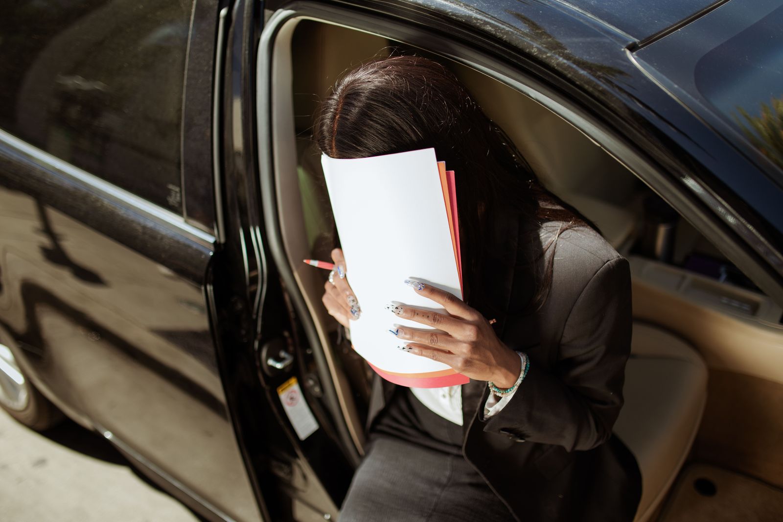An executive reviewing documents in the back seat of a chauffeured sedan between meetings