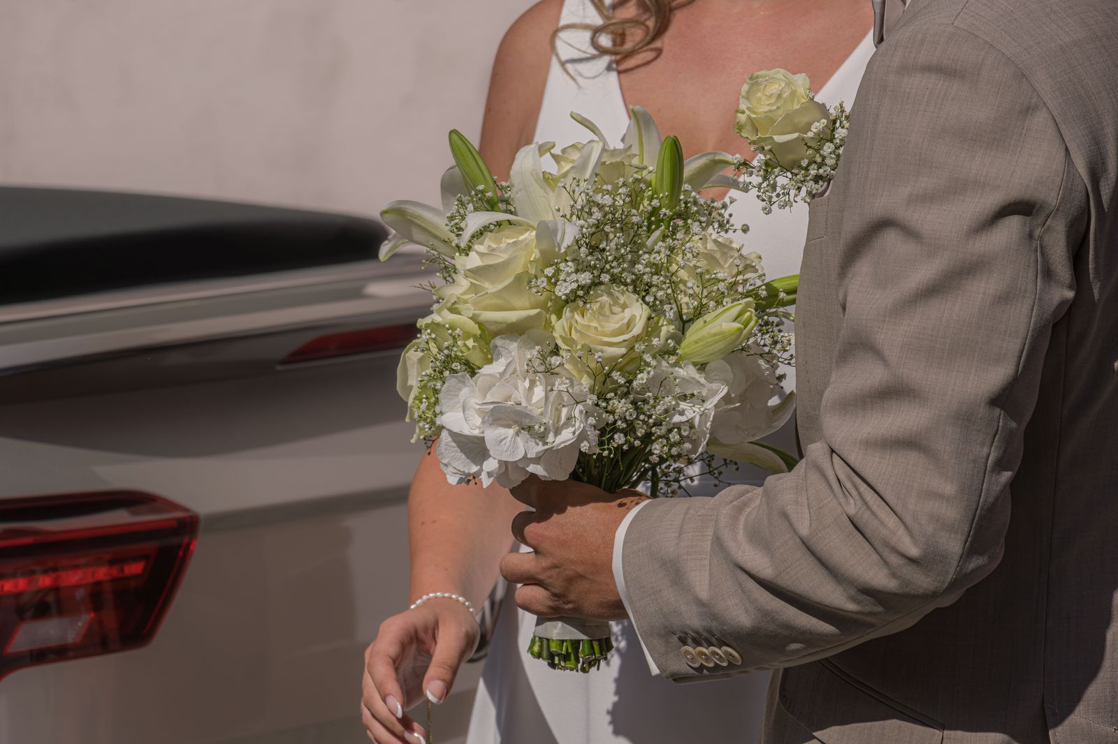 A bride and groom standing beside a black limousine after the ceremony