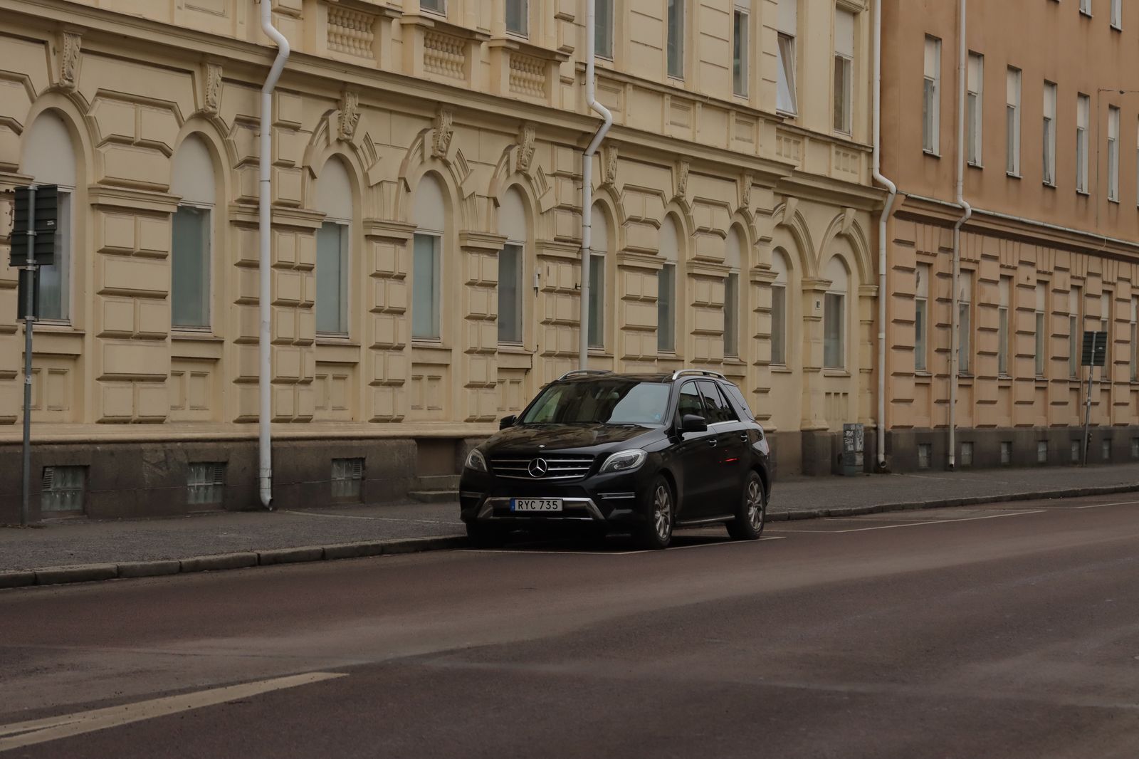 A black executive SUV driving through the city in the early evening