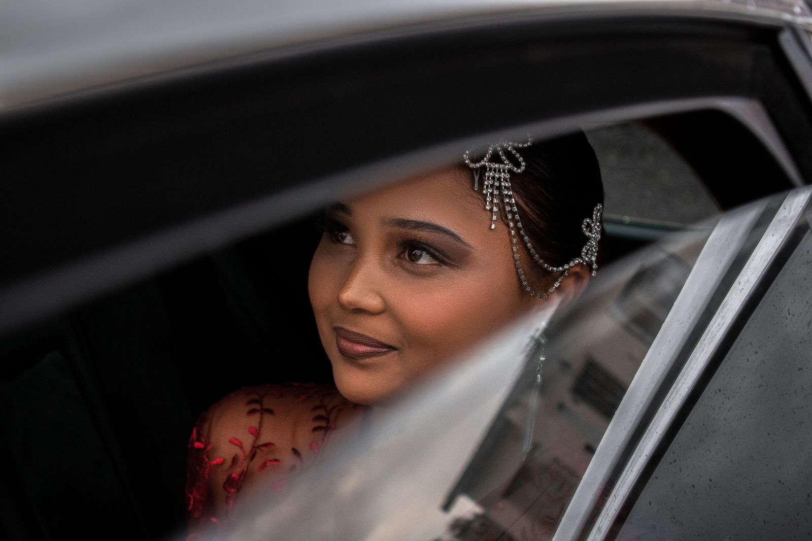 A bride in a white gown stepping out of the rear door of a luxury car